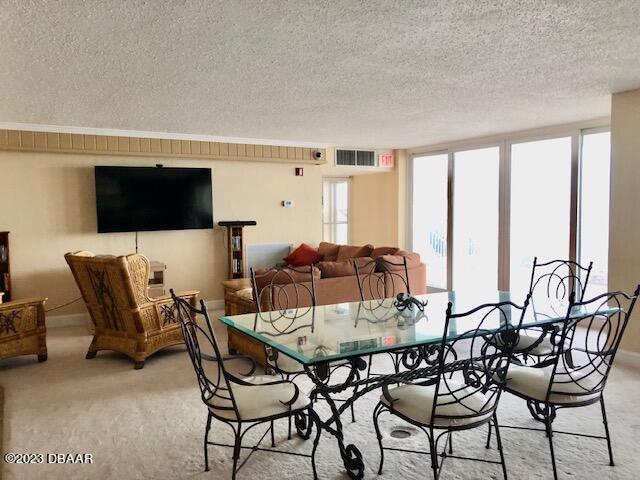 carpeted dining room featuring a textured ceiling