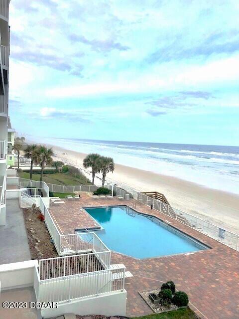 view of swimming pool with a beach view, a water view, and a patio area