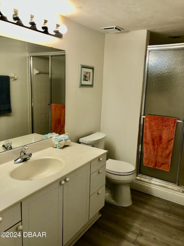 bathroom with walk in shower, vanity, hardwood / wood-style floors, and toilet