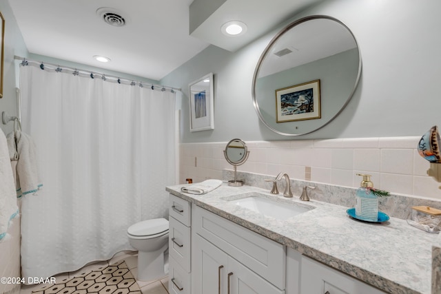 bathroom with tile patterned flooring, vanity, toilet, and tile walls