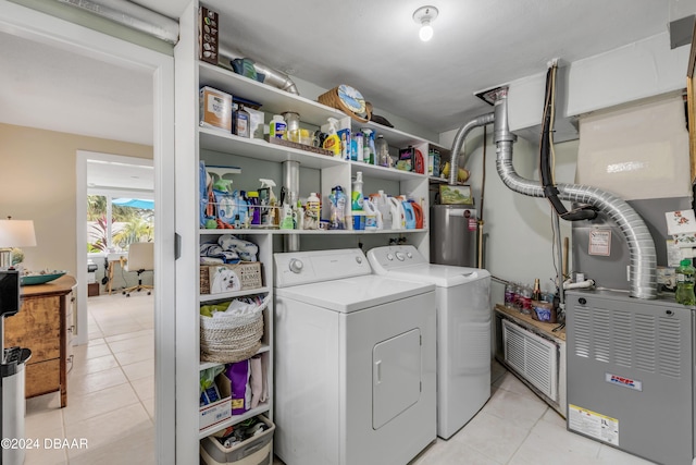 clothes washing area with water heater, washer and clothes dryer, and light tile patterned floors