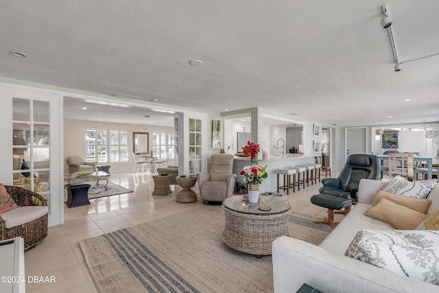 living room with a textured ceiling, light tile patterned floors, sink, and french doors