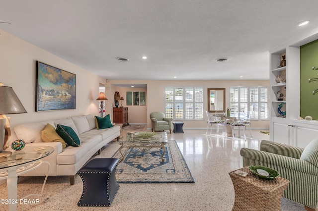 living room with built in shelves and a textured ceiling