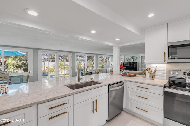 kitchen with white cabinetry, sink, light stone countertops, and appliances with stainless steel finishes