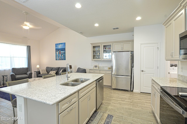 kitchen with light hardwood / wood-style floors, vaulted ceiling, sink, a breakfast bar area, and appliances with stainless steel finishes