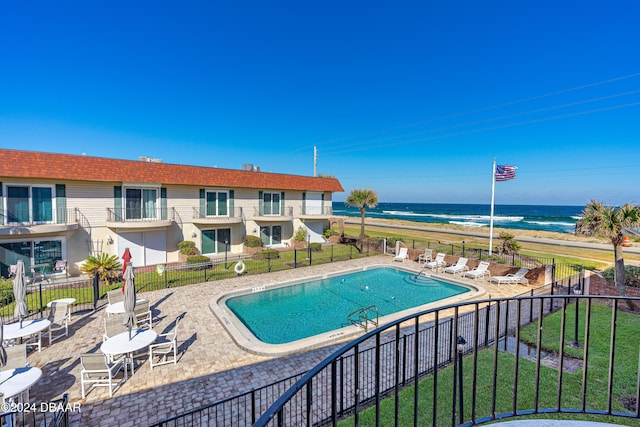 view of pool with a water view, a beach view, and a patio