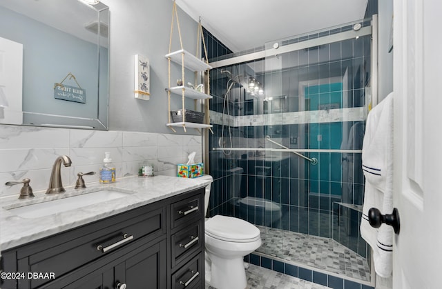 bathroom featuring toilet, decorative backsplash, a shower with door, vanity, and tile walls