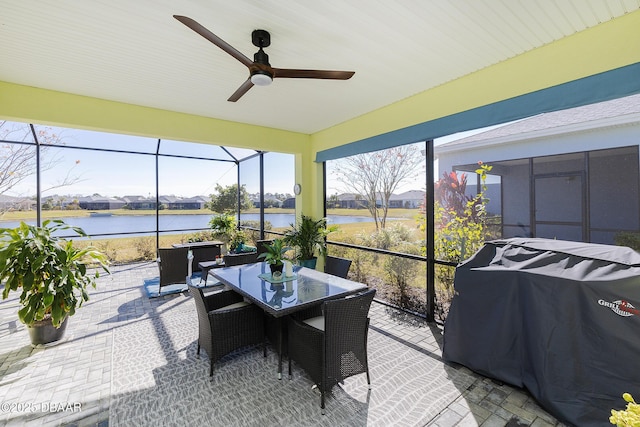 sunroom featuring ceiling fan and a water view