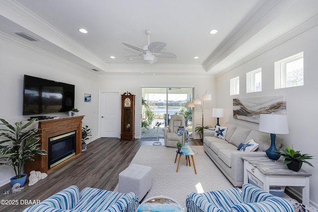 living room with ceiling fan, crown molding, dark hardwood / wood-style floors, and a raised ceiling