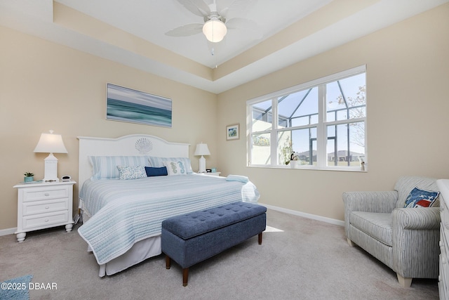 bedroom featuring ceiling fan, light colored carpet, and a tray ceiling