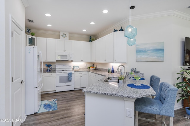 kitchen featuring white appliances, a kitchen bar, white cabinetry, sink, and hanging light fixtures