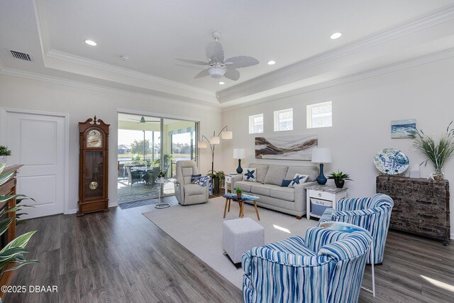 living room with a raised ceiling, ceiling fan, dark hardwood / wood-style flooring, and crown molding