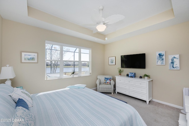 carpeted bedroom featuring ceiling fan and a tray ceiling