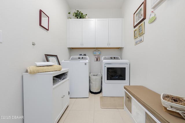 laundry room featuring light tile patterned flooring, washing machine and clothes dryer, and cabinets