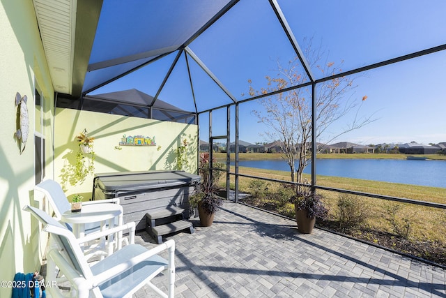 view of patio / terrace with a water view, a hot tub, and a lanai