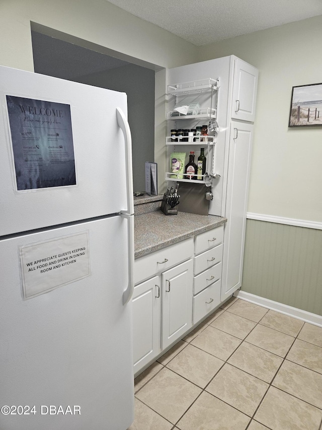 1510 Ocean Shore Blvd Unit 4140, Ormond Beach, FL 32176 - kitchen with freestanding refrigerator, white cabinetry, light tile patterned floors, and wainscoting