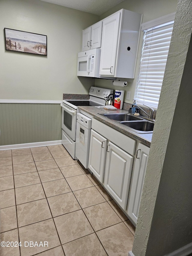 kitchen featuring white cabinets, white appliances, light tile patterned floors, and sink