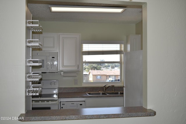 kitchen featuring white cabinets, a textured ceiling, sink, and white appliances