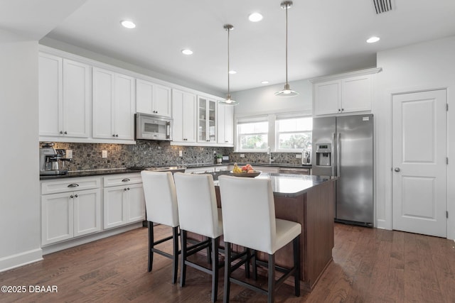 kitchen featuring appliances with stainless steel finishes, tasteful backsplash, and dark wood-type flooring