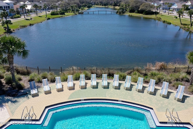 community pool with a water view and fence