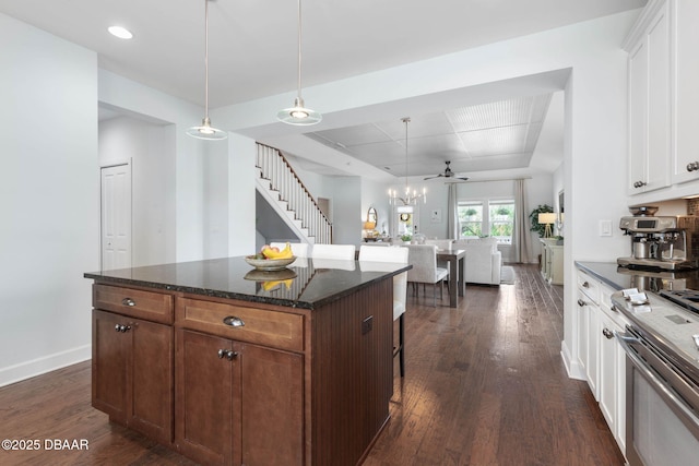 kitchen featuring open floor plan, dark wood-type flooring, a center island, white cabinetry, and stainless steel range