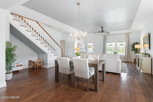 dining area with dark wood-type flooring, baseboards, ceiling fan with notable chandelier, and stairs