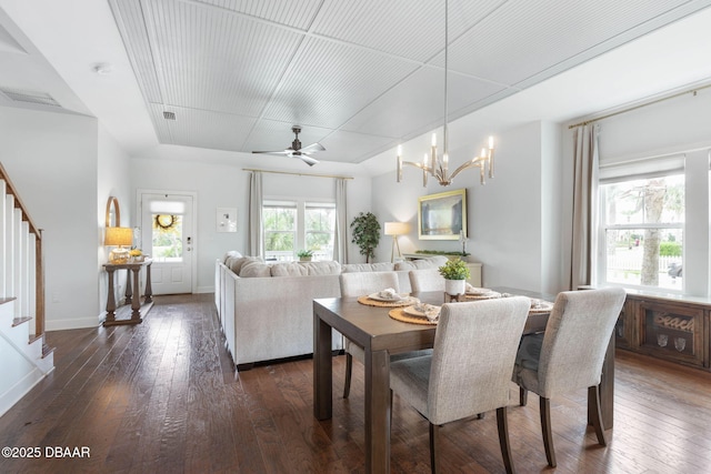 dining room with dark wood-style flooring, visible vents, baseboards, ceiling fan with notable chandelier, and stairs