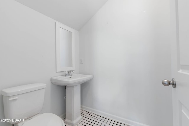 half bathroom featuring toilet, baseboards, and a sink