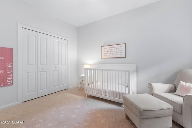 bedroom featuring a closet, a nursery area, baseboards, and carpet flooring
