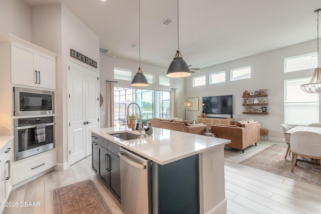 kitchen with pendant lighting, light countertops, appliances with stainless steel finishes, white cabinetry, and a sink