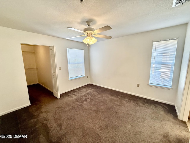 unfurnished bedroom featuring baseboards, visible vents, dark colored carpet, and a textured ceiling