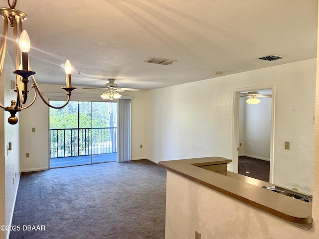 spare room with dark colored carpet, visible vents, and ceiling fan