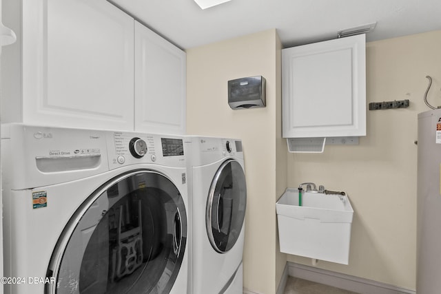 clothes washing area featuring water heater, cabinets, sink, and washer and dryer