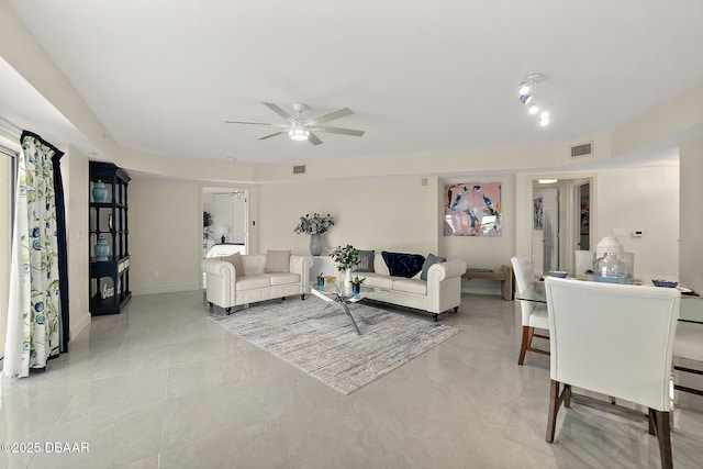 living area featuring baseboards, visible vents, and ceiling fan