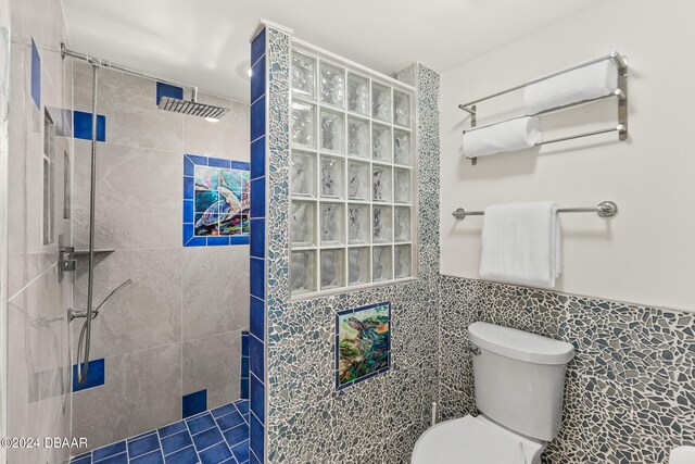 bathroom featuring tile walls, toilet, and a tile shower