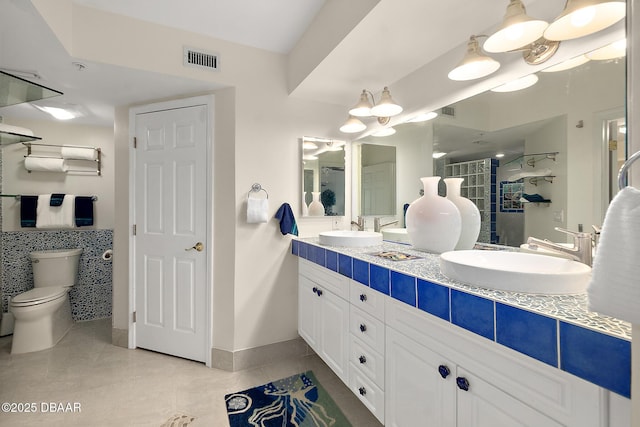 bathroom with double vanity, a sink, tile patterned floors, and visible vents
