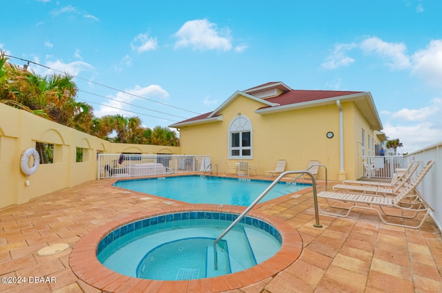 view of swimming pool featuring a hot tub and a patio area