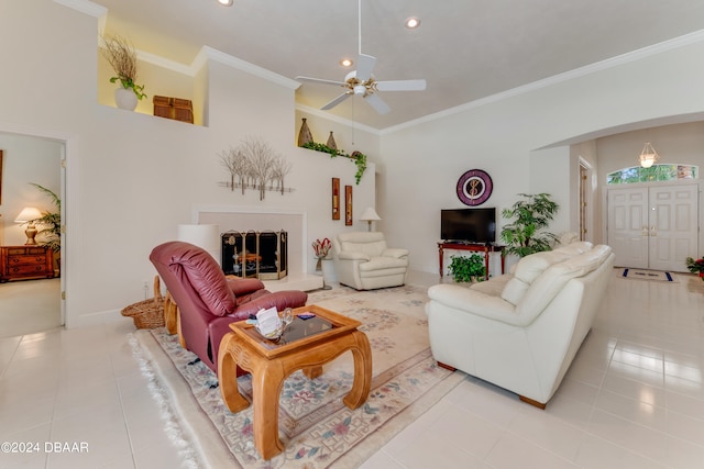 living room featuring a towering ceiling, ceiling fan, light tile patterned floors, and ornamental molding