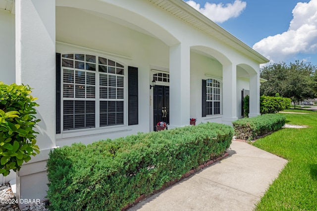 property entrance with a lawn