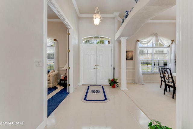 carpeted foyer with ornate columns and crown molding