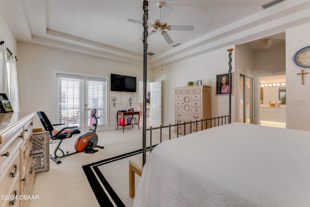 carpeted bedroom with ensuite bathroom, ceiling fan, and a tray ceiling