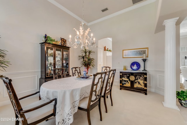 carpeted dining room with a high ceiling, decorative columns, an inviting chandelier, and ornamental molding