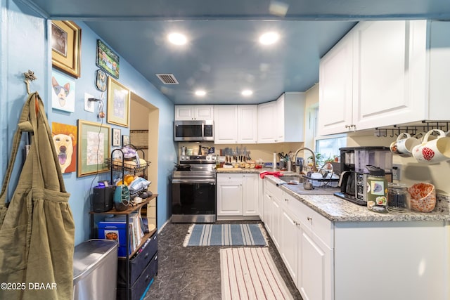 kitchen featuring stainless steel appliances, white cabinetry, sink, and light stone counters