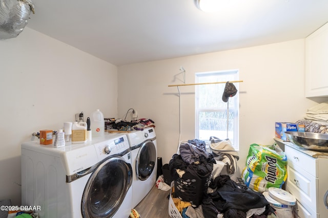 clothes washing area featuring dark wood-type flooring, washing machine and dryer, and cabinets