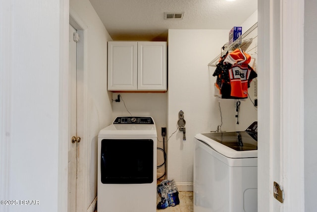 laundry area featuring a textured ceiling, cabinets, and washing machine and clothes dryer