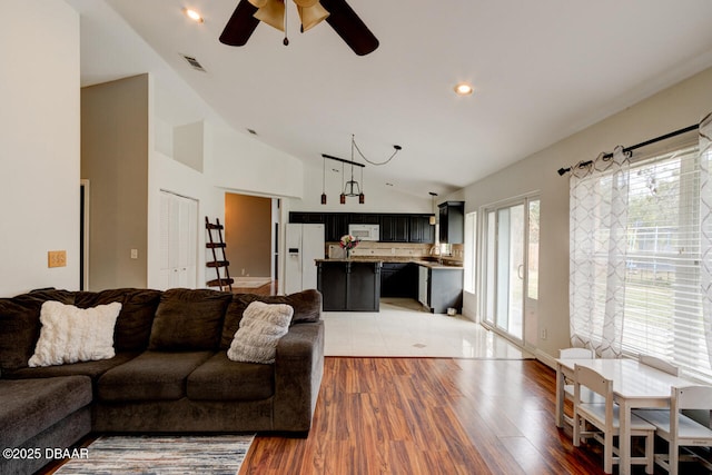 living room with ceiling fan, light wood-type flooring, lofted ceiling, and sink