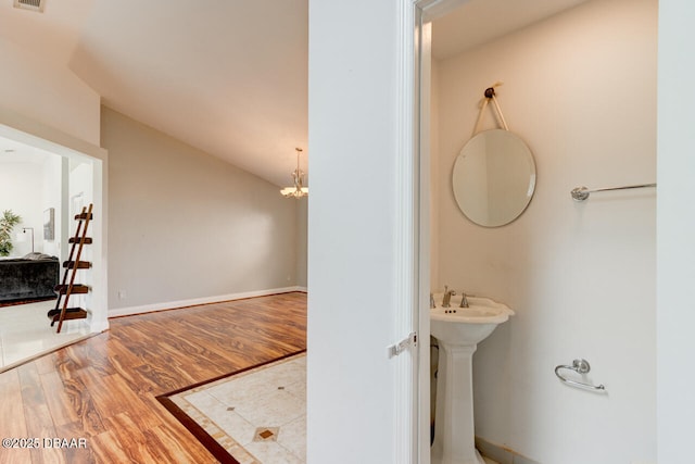 bathroom with lofted ceiling, a chandelier, and hardwood / wood-style floors