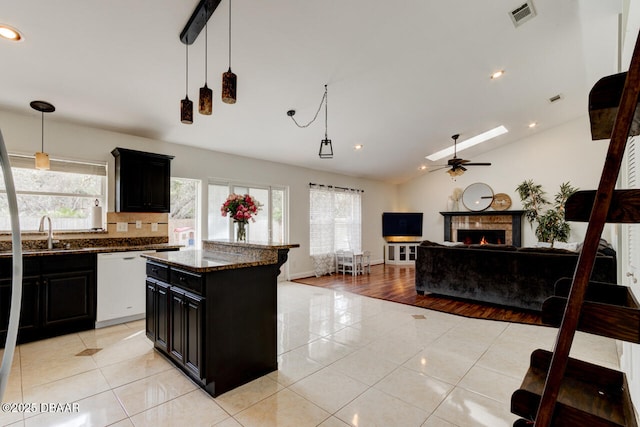 kitchen with dishwasher, a center island, dark stone counters, decorative light fixtures, and light tile patterned flooring