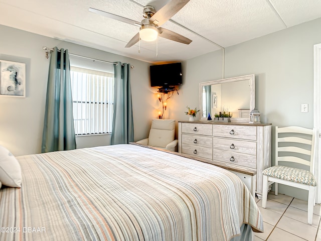 bedroom with a textured ceiling, light tile patterned floors, and ceiling fan