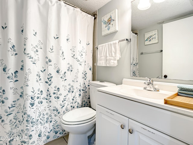 bathroom featuring tile patterned flooring, vanity, a textured ceiling, and toilet